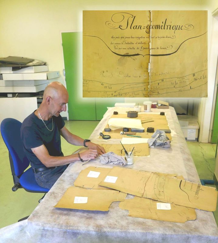Laurent à la tâche, en train de restaurer le "Plan géométrique des prés qui pour leur irrigation ont droit à la prise d’eau des sources de Fontenilles", à Allègre (registre d'actes notariés 3 E 480/136) 